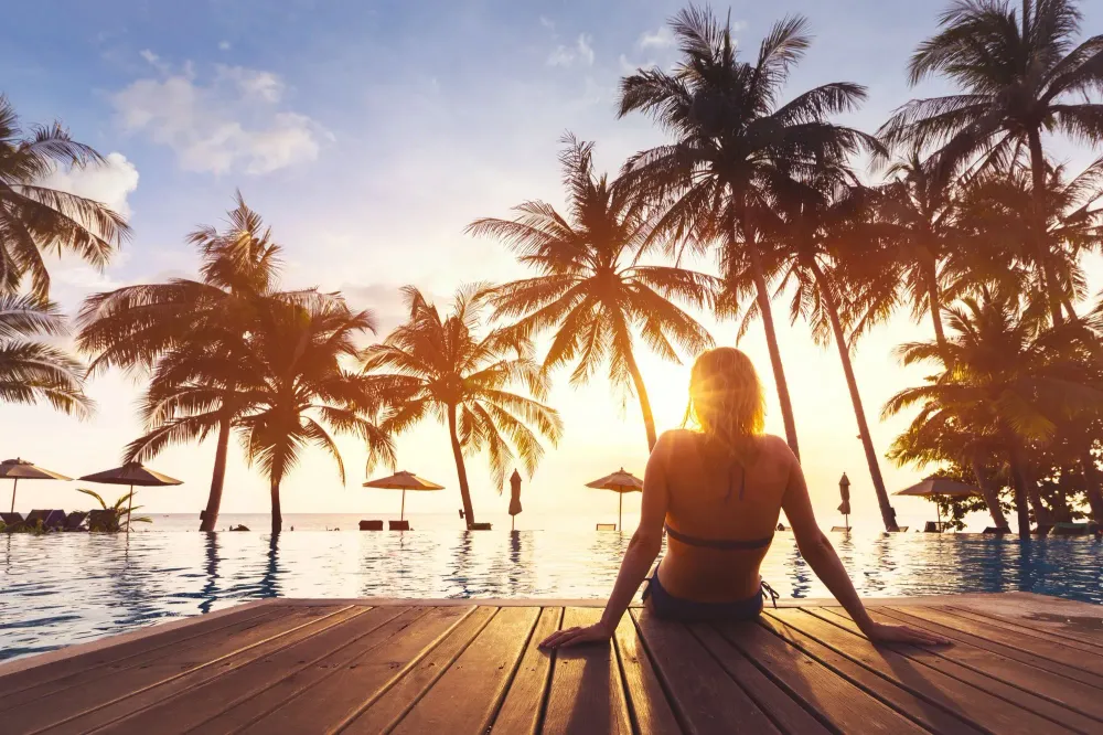 Woman relaxing on a pier in front of a pool and palm trees